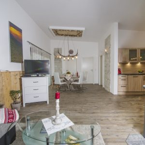 Wohn- und Essbereich mit Tisch, Fernseher und Küchenzeile